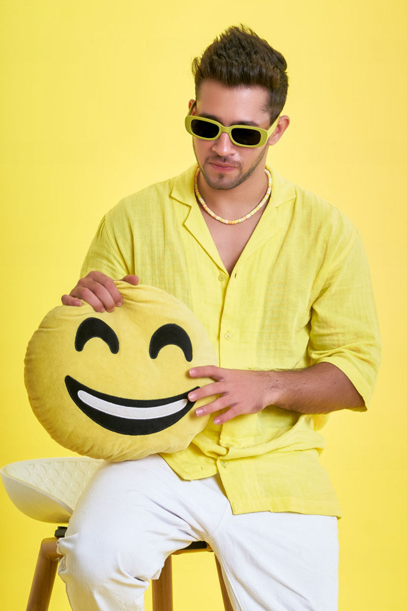 Guy wearing an oversized yellow unisex shirt with a soft toy which is a laughing emoji