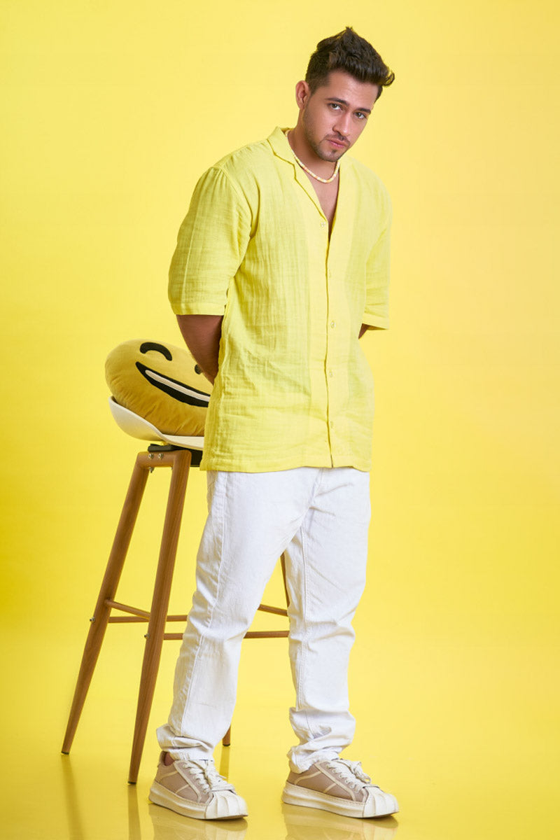 Guy wearing an oversized yellow unisex shirt in a side ways pose