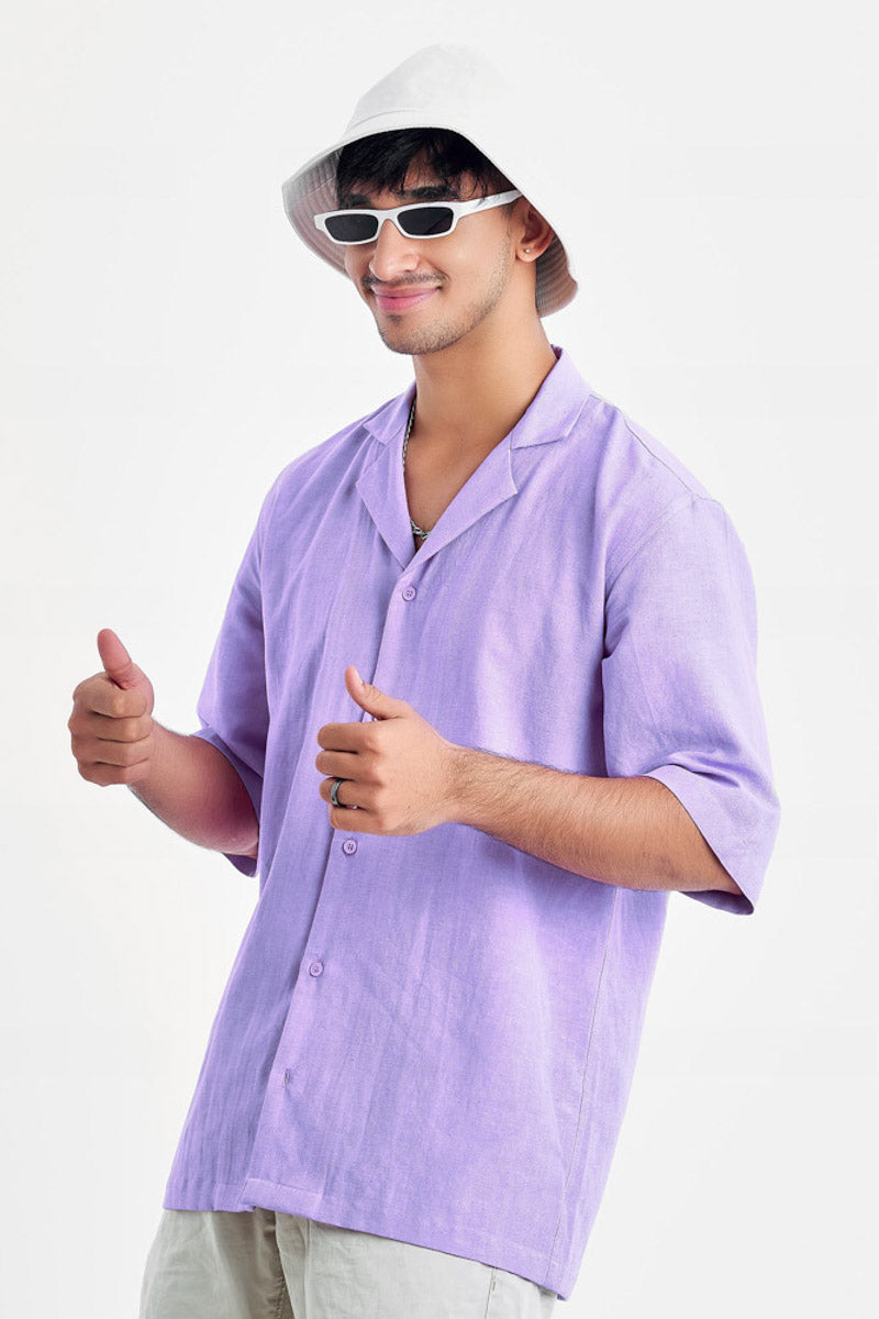 Person wearing an oversized lavender shirt with black glasses and white hat giving a thumbs up